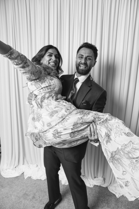 A groom lifts his laughing bride, her arm flung out wide